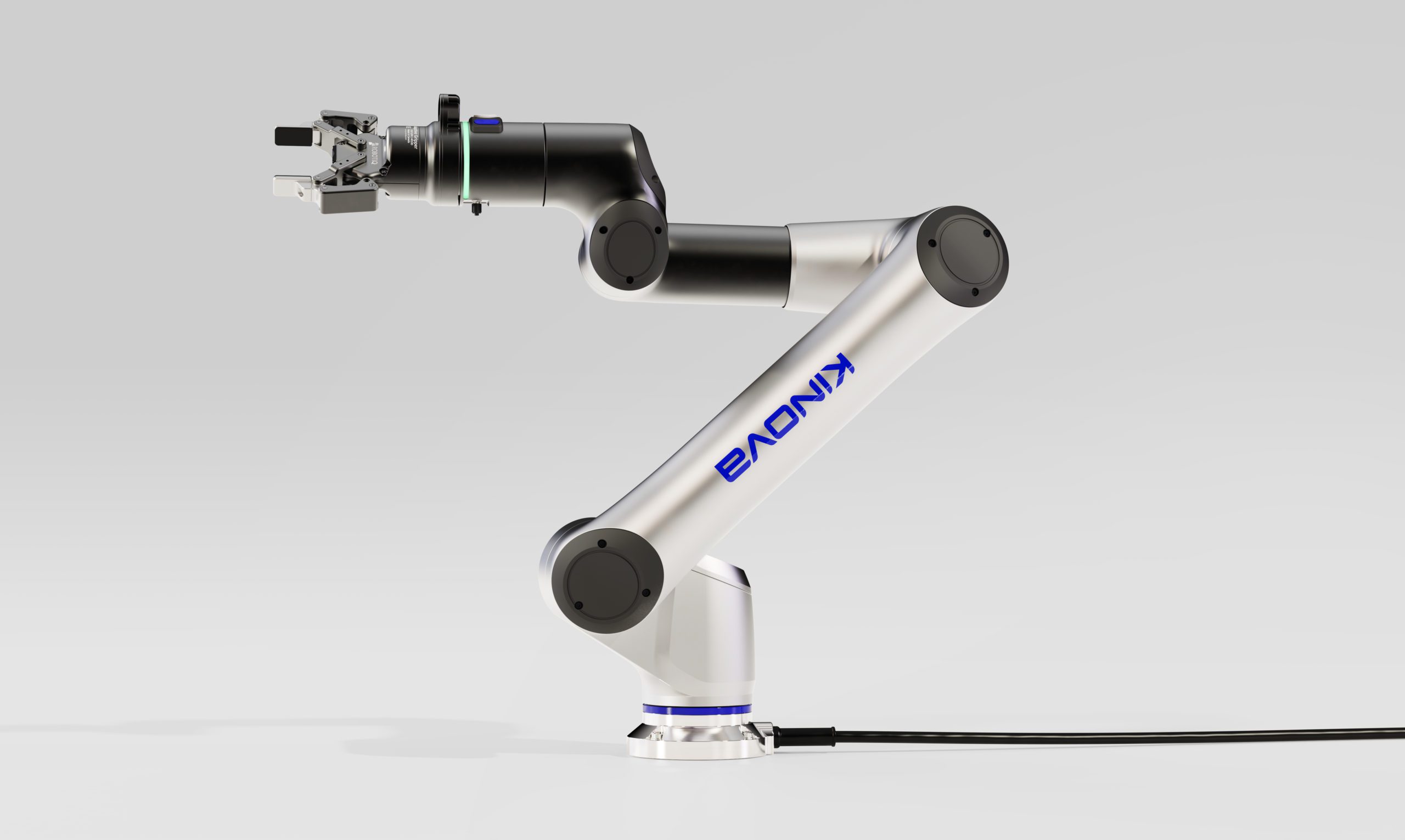 A sleek, silver robotic arm with black joints and a mechanical gripper, labeled KINOVA, designed by an agence de design industriel à Montréal, stands on a round base with a power cable, set against a plain light gray background.