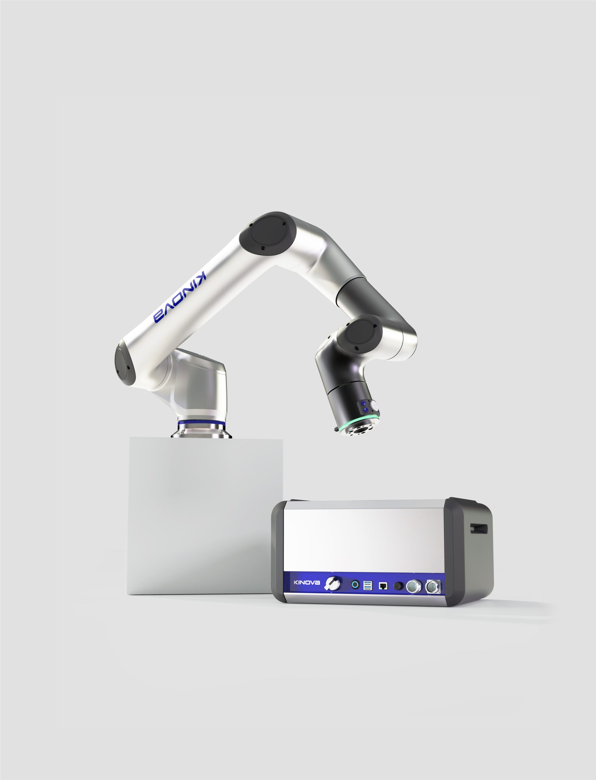 Un bras robotique étiqueté KINOVA est monté sur un bloc blanc, à côté d'un appareil électronique rectangulaire aux accents bleus, conçu par une Agence de développement de produits à Montréal, sur un fond gris clair uni.