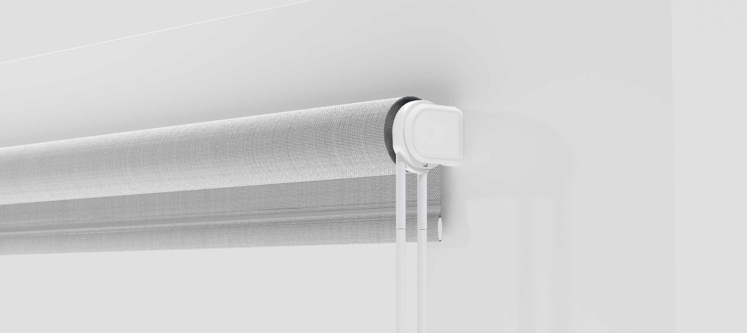 Gros plan sur un store moderne et minimaliste monté sur un mur blanc, au design épuré avec un tissu texturé et un simple mécanisme de support blanc, par une agence de design industriel à Montréal.