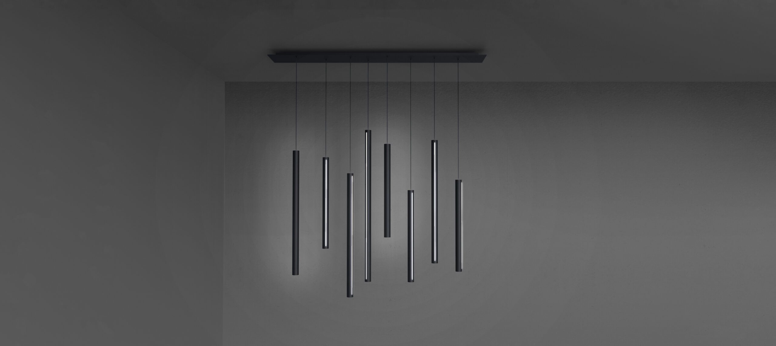Luminaire suspendu minimaliste composé de neuf tiges minces suspendues à des longueurs variées à un support de plafond rectangulaire - une pièce inspirante pour toute Agence de développement de produits à Montréal à la recherche de solutions d'éclairage raffinées et modernes.