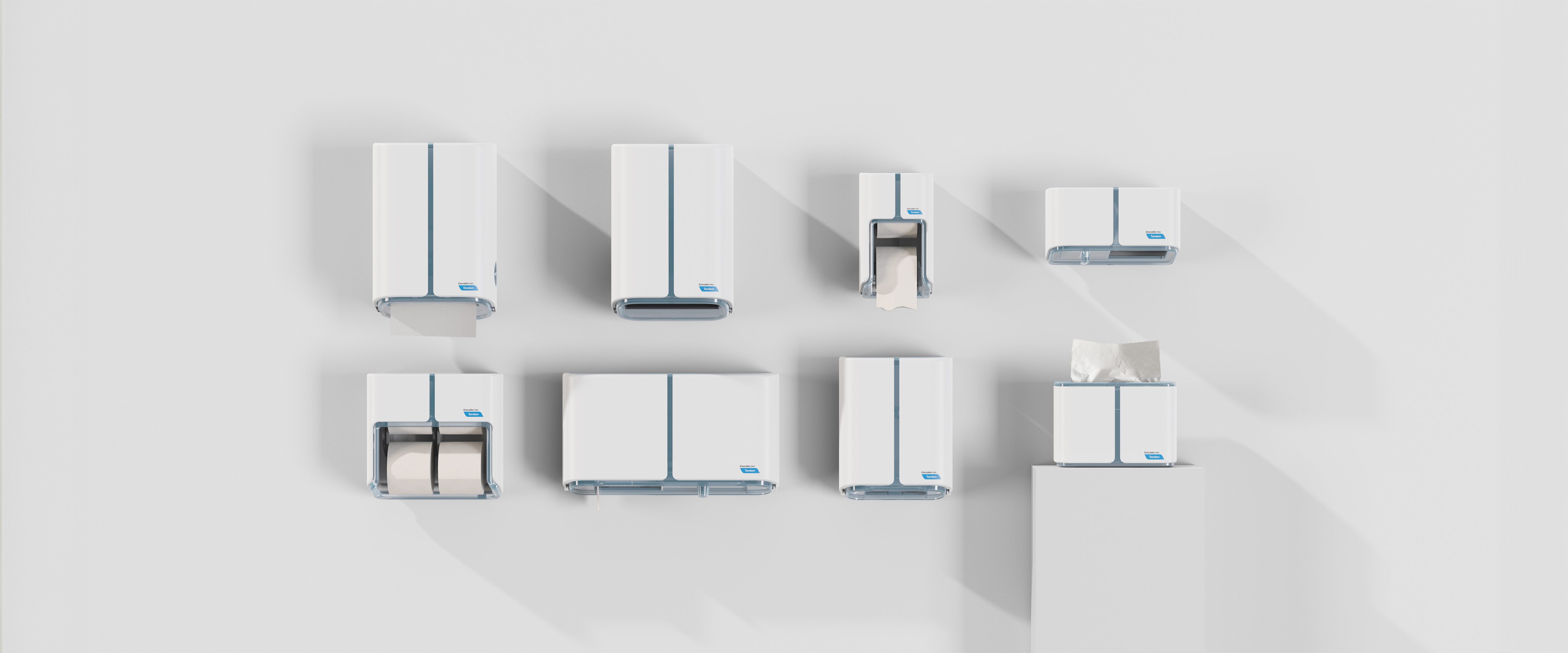 Sept distributeurs blancs et bleus sont montés sur un mur blanc en deux rangées, projetant des ombres. Le distributeur surélevé en bas à droite présente des mouchoirs en papier visibles - un agencement qui reflète la touche raffinée d'une Agence de design industriel à Montréal.